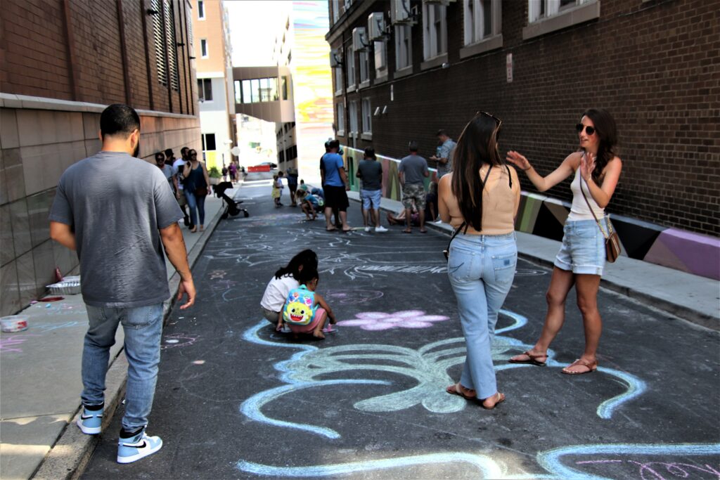 People in an alley decorated with chalk drawings