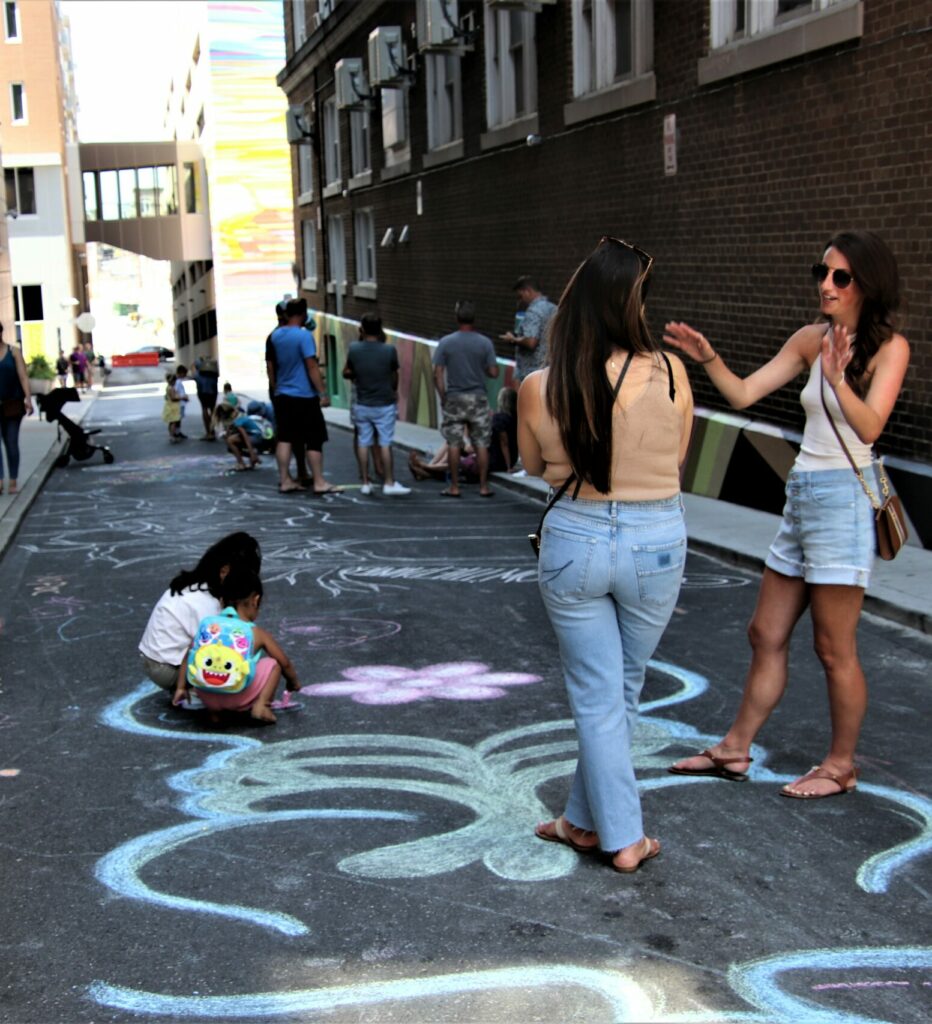 People in an alley decorated with chalk drawings